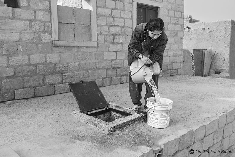 A young lady procuring Viprasar water stored in a household tanka for domestic use in Netsi village, Thar Desert, Jaisalmer, Rajasthan, India